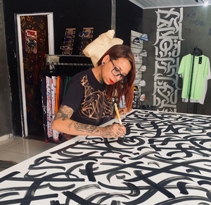 Artist Mari Montenero painting an art piece featuring he signature style Caligraffiti