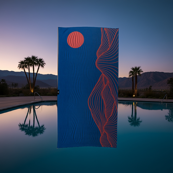 Blue towel with red abstract desert mountain and sunset design by a pool at dusk