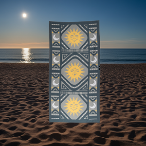 Decorative towel with sun and moon patterns on a beach at sunset