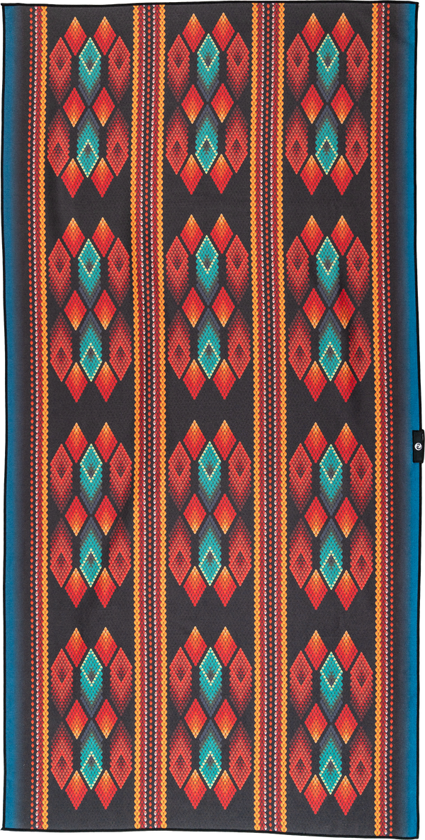 A towel with a bold geometric design featuring diamond patterns in vibrant shades of red, orange, and teal on a black background. The repeating diamond shapes are accentuated by smaller colorful details, creating a visually striking and dynamic look.