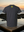Gray t-shirt with a yellow logo on the back, placed on a rock by the ocean at sunset.