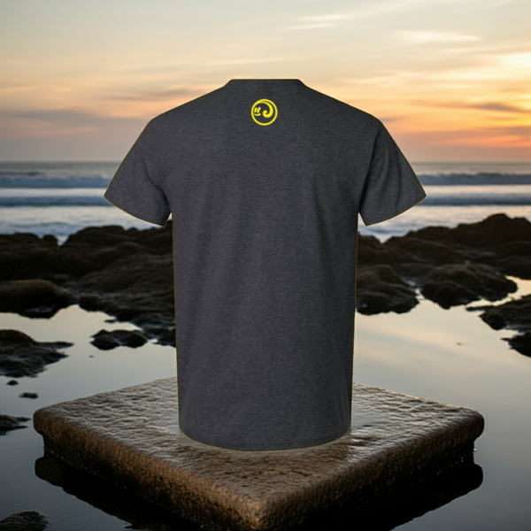 Gray t-shirt with a yellow logo on the back, placed on a rock by the ocean at sunset.