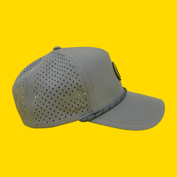 Side view of a gray happy faced cap with perforated design on a yellow background