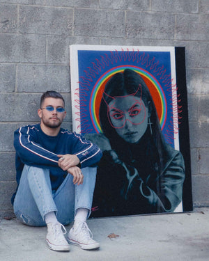 Local Malibu artist Hunter Blaze Pearson sitting in front of his painting of a girl in a leather jacket with a devil maskAn image of the artist Flekz for Happy Faced Towels.