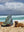 A man uses a Happy Faced Towel to sheild himself from the sun on the beach in Hawaii with his dogs