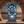 Decorative towel with floral and crab design in front of a stone archway with a beach view.