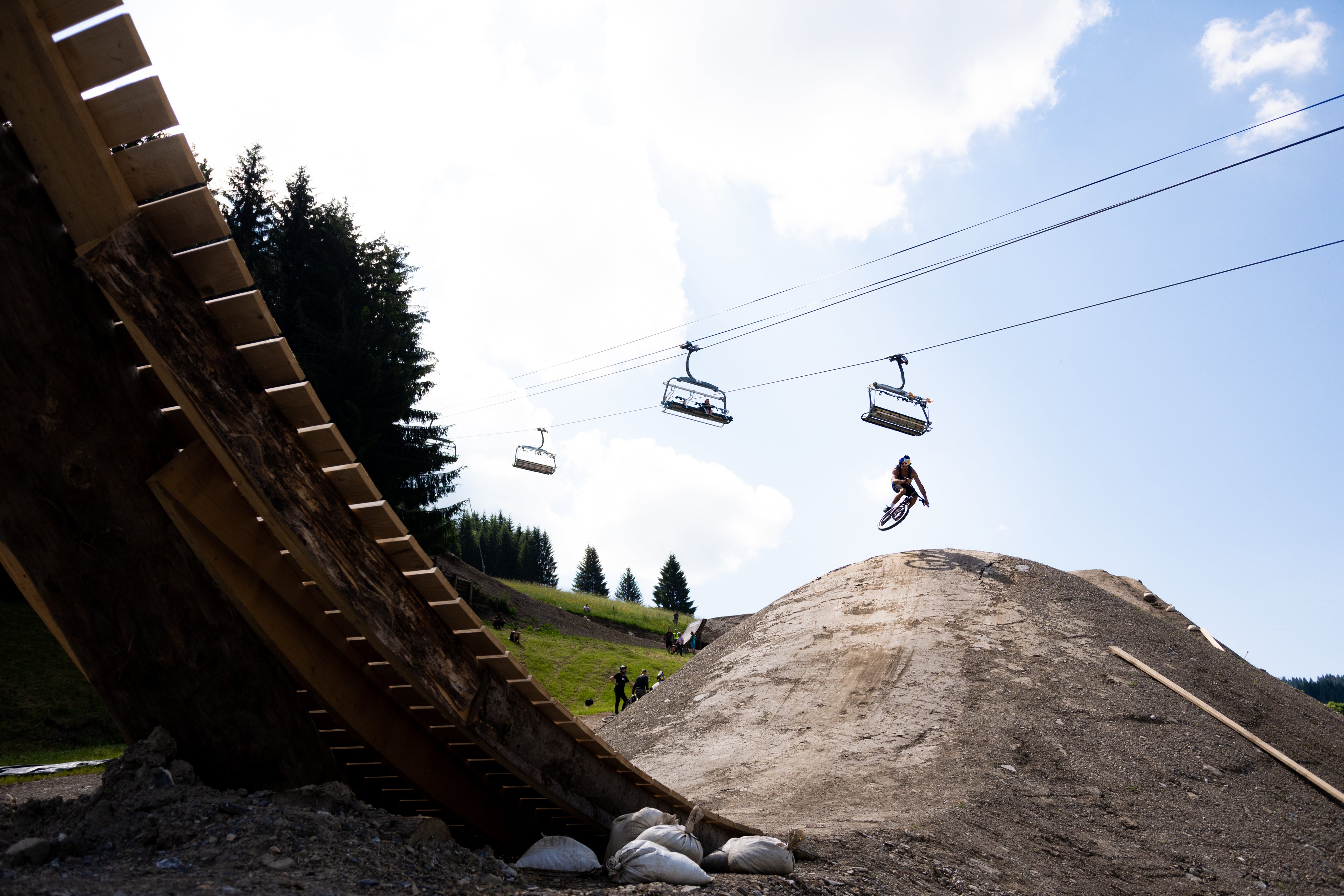 Mountain biker riding through a bike park beneath a chair lift