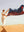 A smiling woman stands on a dune in the Sahara Desert beach holding a Happy Faced Towel that blows in the warm wind